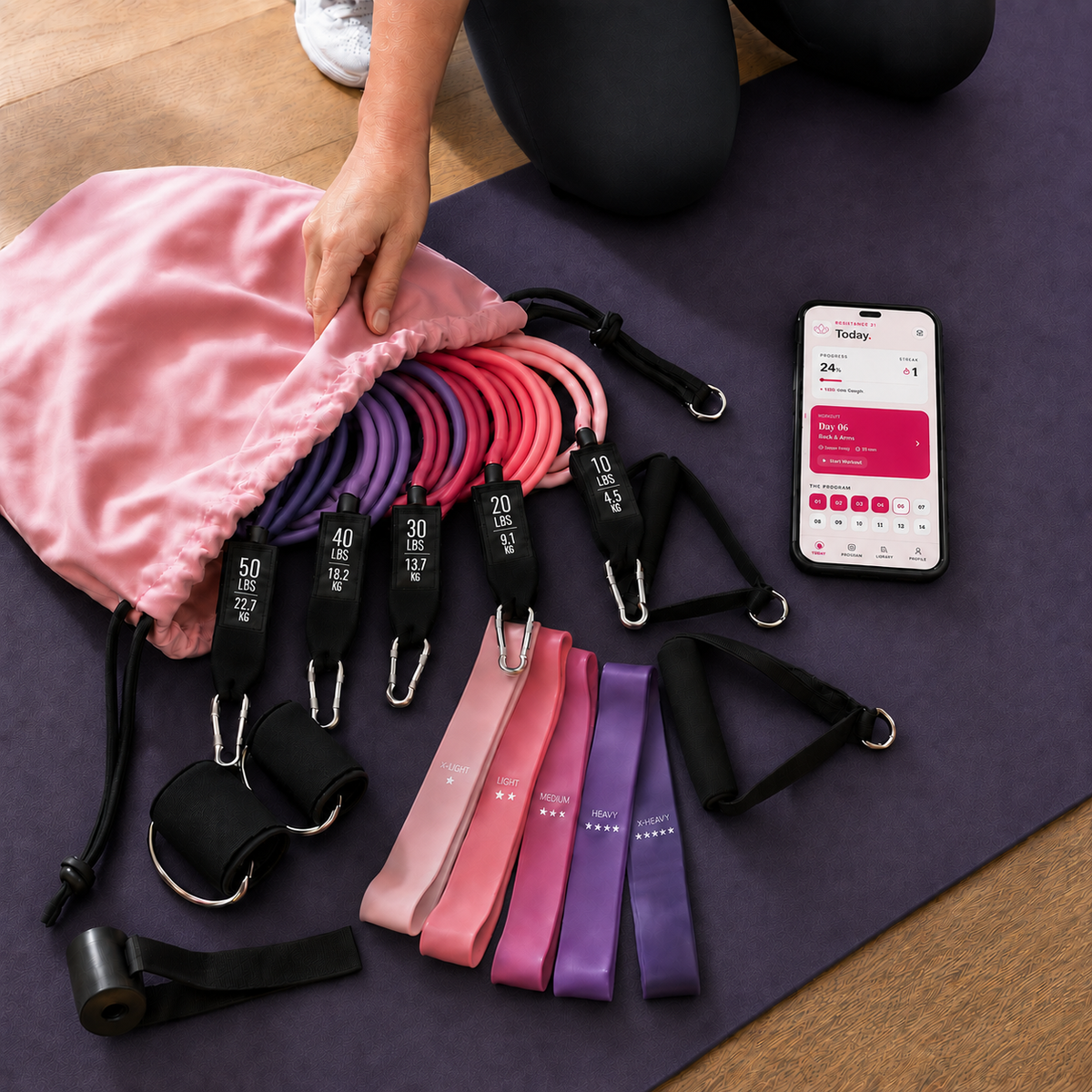 Movita complete home-training system with woman, resistance bands, carry pouch and Resistance21 shown on a phone